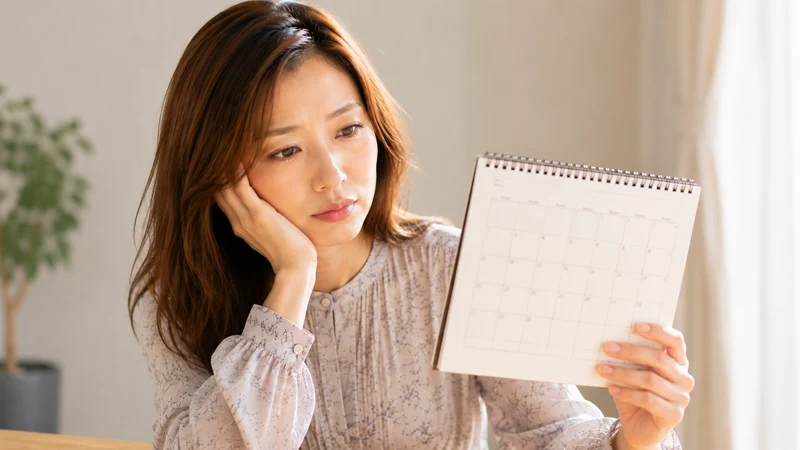 深刻な表情でカレンダーを見つめる女性